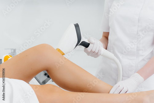 A beautiful young girl will undergo laser hair removal with modern equipment in a Spa salon. Beauty salon. Body care photo