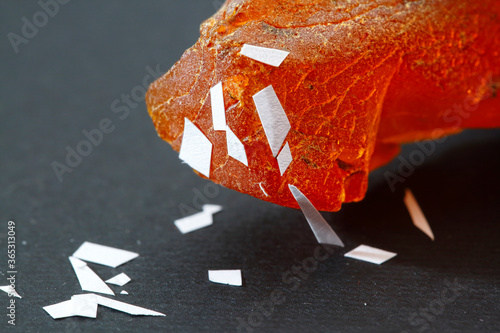 Physical properties of amber. Sun stone properties. An electrified piece of amber attracts pieces of paper against a gray background. Magnetized resin. Natural mineral for jewelers. Copal