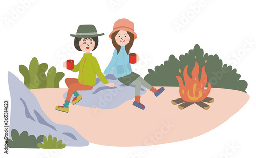 キャンプで焚き火をしてコーヒーを飲む若い2人の女性