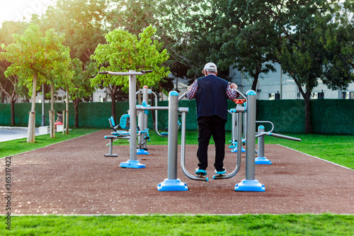 Old man doing leg workout with workout equipment in public park day time