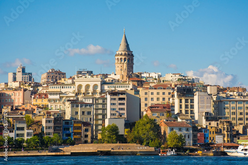 Istanbul, Turkey - September 6th 2019. Locals fish and relax on the Beyoglu waterfront. Viewed from Galata Bridge with Galata Tower central 