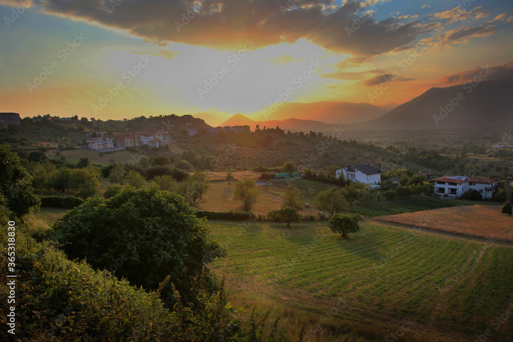 Obraz premium a view of the hills and fields in Buccino, Italy during a colorful sunset.