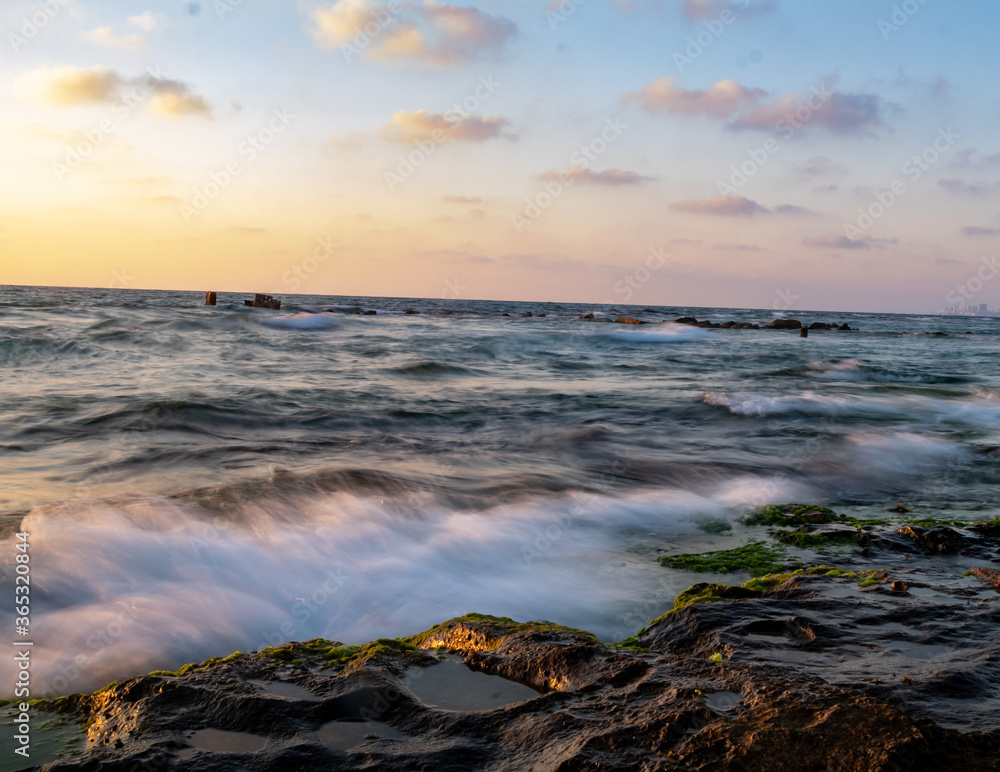 water splash on rocks sunset over the sea