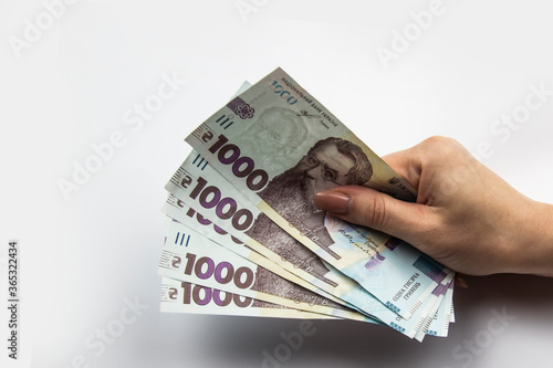 Female hand holds a five thousand hryvnia. Ukrainian currency with woman's hand against a white background. Five thousand hryvnia with one thousand hryvnia five bills. Ukrainian money. Banknotes