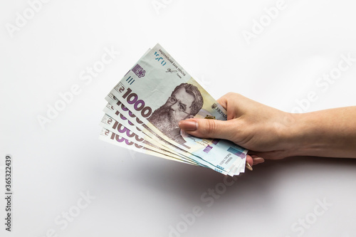 Female hand holds a five thousand hryvnia. Ukrainian currency with woman's hand against a white background. Five thousand hryvnia with one thousand hryvnia five bills. Ukrainian money. Banknotes