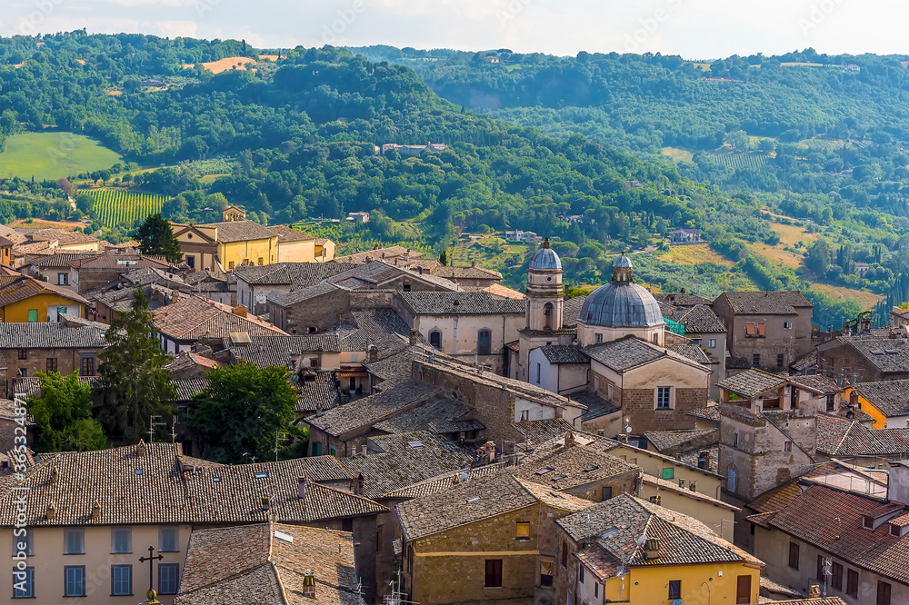 A jumble of roof tops rise above the surrounding countryside in Orvieto, Italy in summer