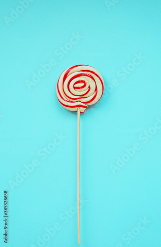 a red and white spiral heart lollipop on blue background, flat lay minimal concept, trendy pop art style photo, isolated, copy space