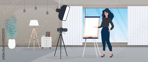 The girl is giving a presentation in front of the camera. The teacher conducts a lesson online. The concept of blogs, online training and conferences. Camera on a tripod, softbox.