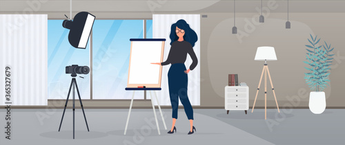 The girl is giving a presentation in front of the camera. The teacher conducts a lesson online. The concept of blogs, online training and conferences. Camera on a tripod, softbox.