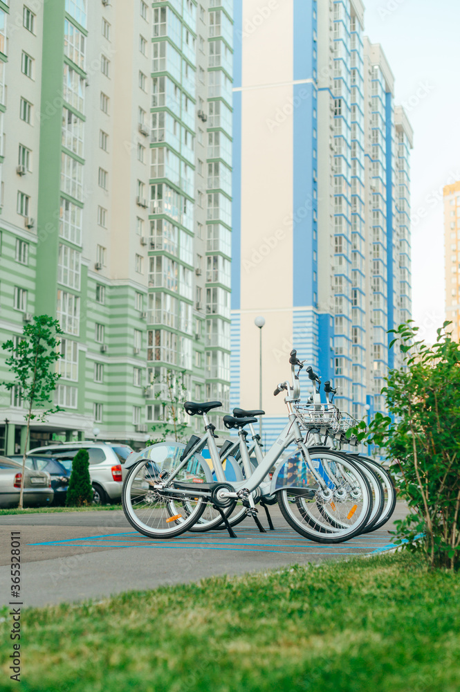 Row of bicycles for sharing on the background of colorful apartment buildings. Eco transport. Bicycle rental concept Row of bicycles for sharing on the background of colorful apartment buildings. Eco transport. Bicycle rental concept