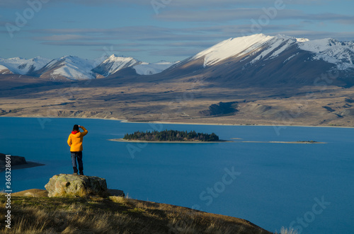 Girl in yellow jacket looking at Lake Tekapo from Mount John observatory, South Island, New Zealand