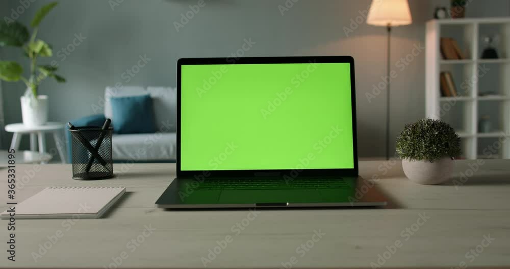Modern laptop with mock up chroma key green screen on table of living
