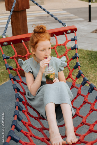 Red-haired girl swinging in a hammock