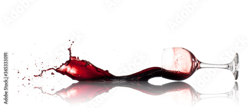 Burgundy red wine pouring onto a reflective white surface