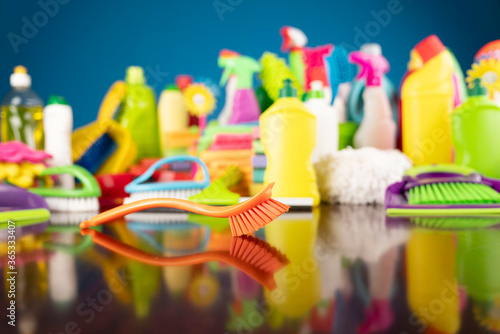 House and office cleaning theme. Colorful cleaning kit on shing brown table and blue background.