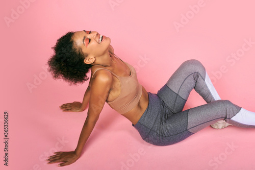 Happy sportive black woman chilling after .workout after pink background. photo