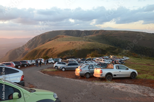 Fototapeta Naklejka Na Ścianę i Meble -  Cars lined up at sunset on a curve in Topo do Mundo (translated to Top of the World) in Minas Gerais