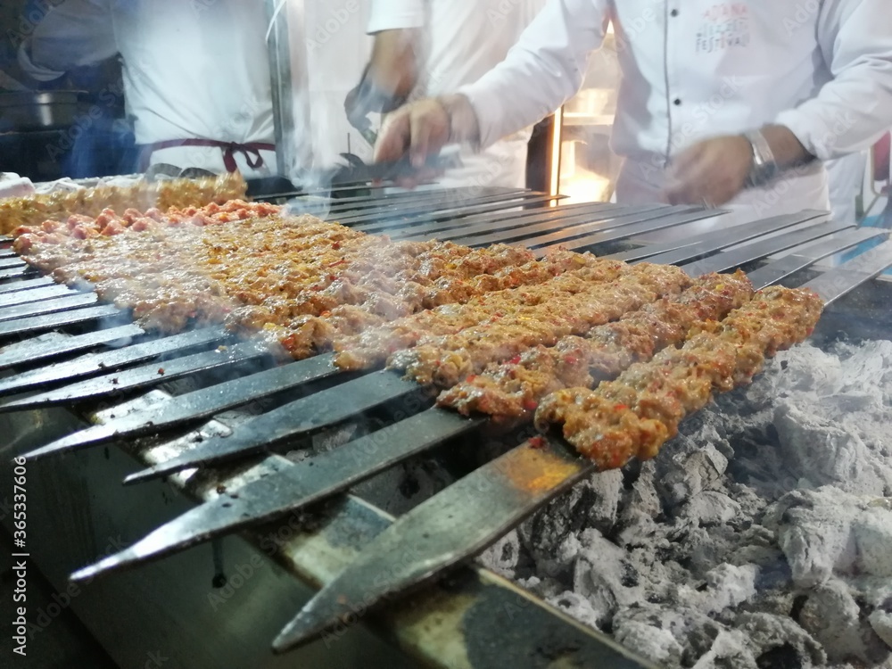 Cooking Adana kebabs on the restaurant style grill
