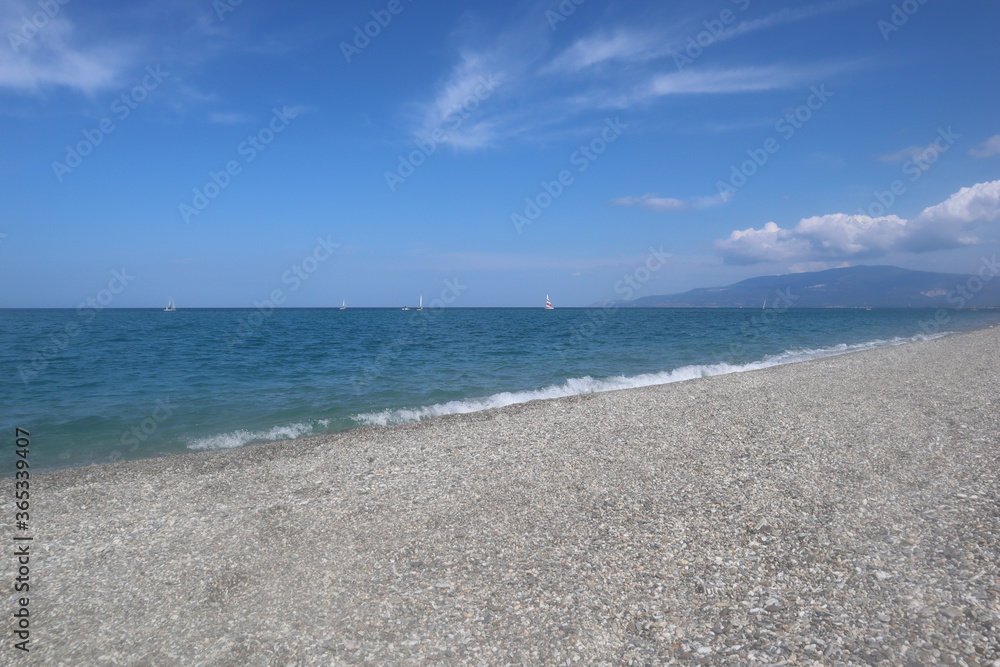 Beach on a summer day, blue sea and sky with white clouds, vacation at the sea, Calabria, Italy