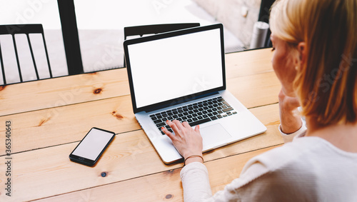 Female person sitting front open laptop computer and smartphone with blank empty screen for your information or content, modern businesswoman work in internet via notebook, student at coffee shop