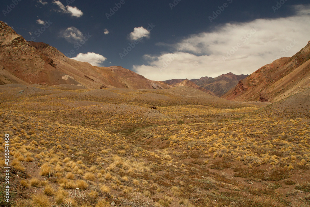 Golden valley. Panorama view of the rocky mountains, hills and yellow grassland in autumn.