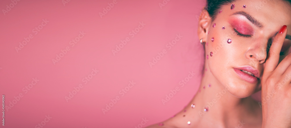 Girl with pink make-up and rhinestones on her face on a pink background Girl with pink make-up and rhinestones on her face on a pink background