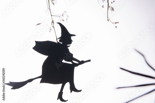 Tablou canvas Black paper silhouette of a witch flying to Sabbath on Halloween night on white background
