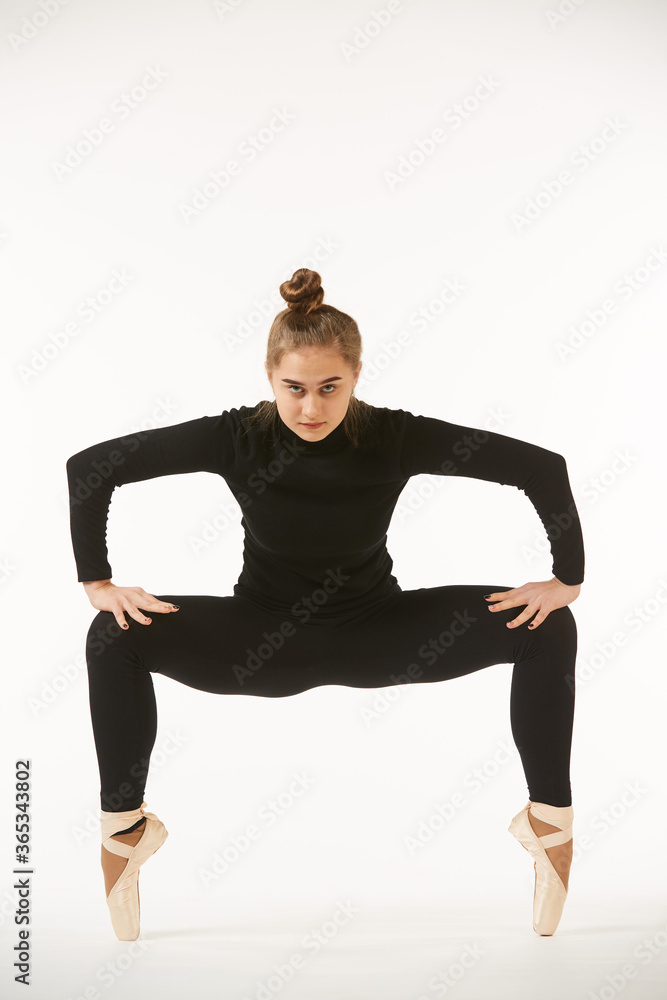 A girl in black clothes and Pointe shoes on a white isolated background performs dance and ballet poses and movements. A girl in black clothes and Pointe shoes on a white isolated background performs dance and ballet poses and movements.