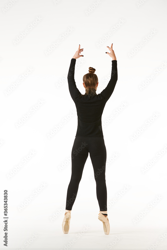 A girl in black clothes and Pointe shoes on a white isolated background performs dance and ballet poses and movements. A girl in black clothes and Pointe shoes on a white isolated background performs dance and ballet poses and movements.