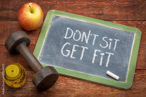 Fototapeta Naklejka Na Ścianę i Meble -  do not sit, get fit  - white chalk text on a slate blackboard sign against weathered wood with a dumbbell, apple and tape measure, fitness, healthy lifestyle or weight loss concept