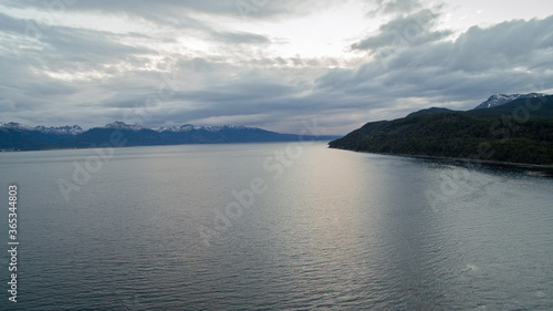 The ocean at nightfall. Aerial view of the sea, forest, mountains and sunlight reflection in water at sunset. 