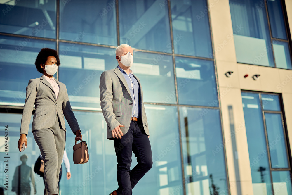 Business colleagues with protective face masks leaving office building. Business colleagues with protective face masks leaving office building.