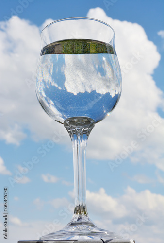Glass of water with sky reflection