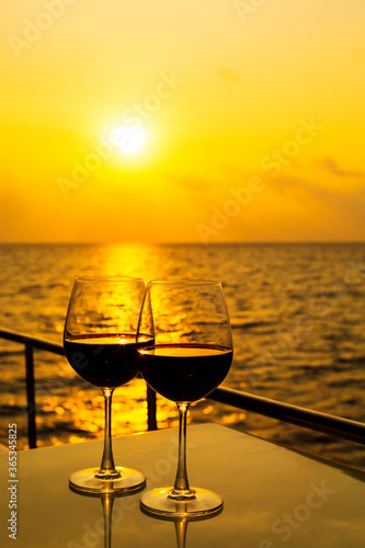 Glasses, red wine and tropical sunset with sea background, nobody.
