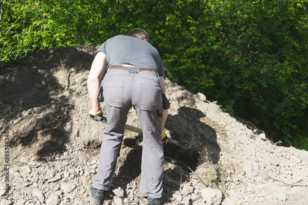 A back view of man spreading soil masse around. A back view of man spreading soil masse around.