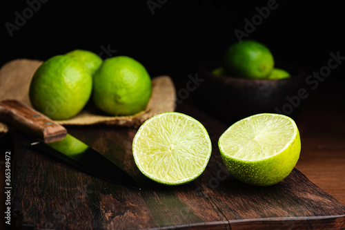 Fresh, raw and organic sliced green lemon in focus with other lemons in composition