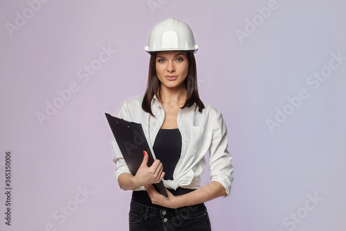 construction girl in a white helmet, holding a folder. the concept of a business woman who understands construction, repair and modernization..