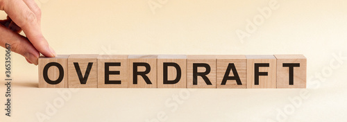 Letter block in word overdraft on paper yellow background, front view