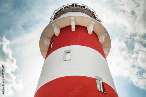 A red and white lighthouse against a blue sky.