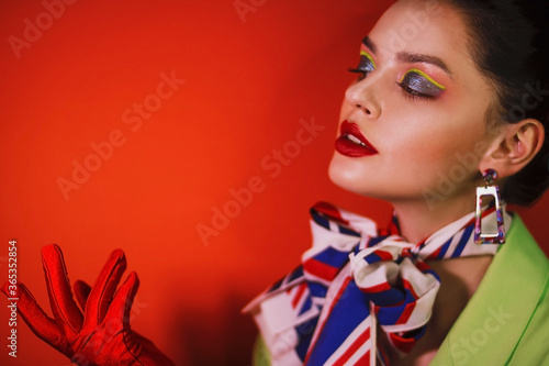 Girl in a green suit with a scarf around her neck and with a cigarette in her hands on a red background © Ирина Сизоненко
