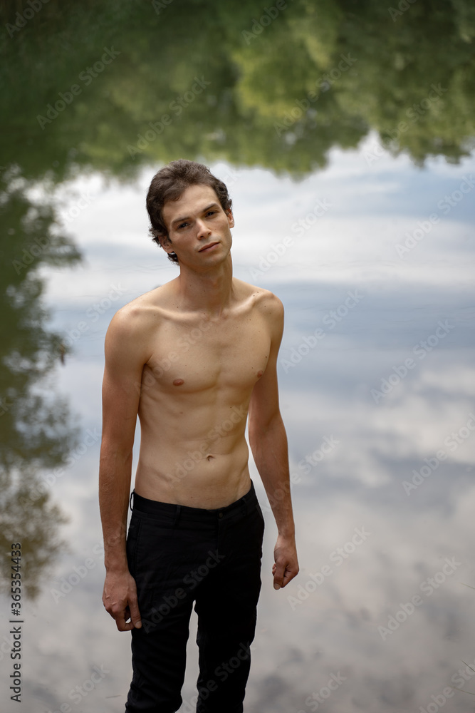 Portrait of shirtless handsome man standing against lake in forest Portrait of shirtless handsome man standing against lake in forest