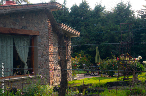 Casa de campo con arboles y flores dia soleado y cercado