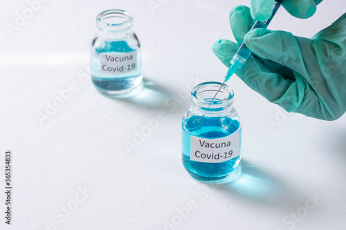 concepto de vacuna del covid 19 con una mano con guantes médicos sacando muestra del frasco con una jeringa