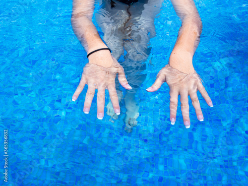 Woman hands with manicure in the swimming pool