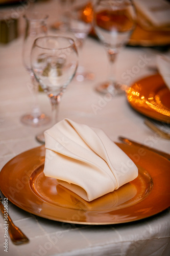 Wedding table set with golden glass plates and folded napkin