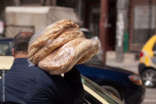 Φωτογραφία A Syrian baker is carrying  fresh made traditional flat breads in the street