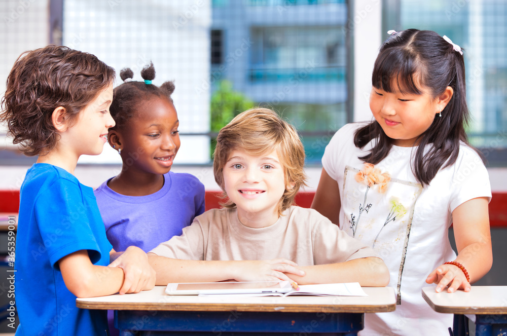 Elementary school scene. Multi ethnic classmates in the classroom learning together Elementary school scene. Multi ethnic classmates in the classroom learning together