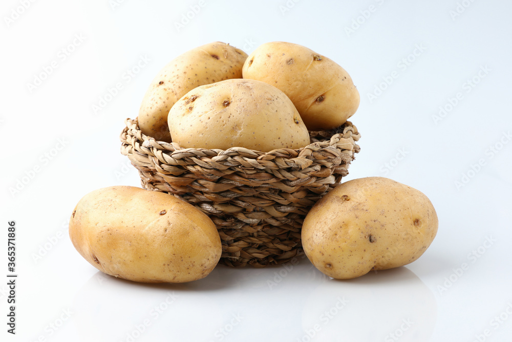 Raw potatoes organic tuber is a vegetarian harvest new on the basket on white background. Raw potatoes organic tuber is a vegetarian harvest new on the basket on white background.
