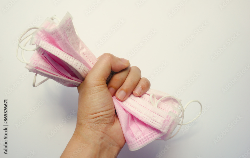 Fototapeta premium Hand holding medical face masks tightly on white background. Healthcare medical Coronavirus quarantine, hygiene concept