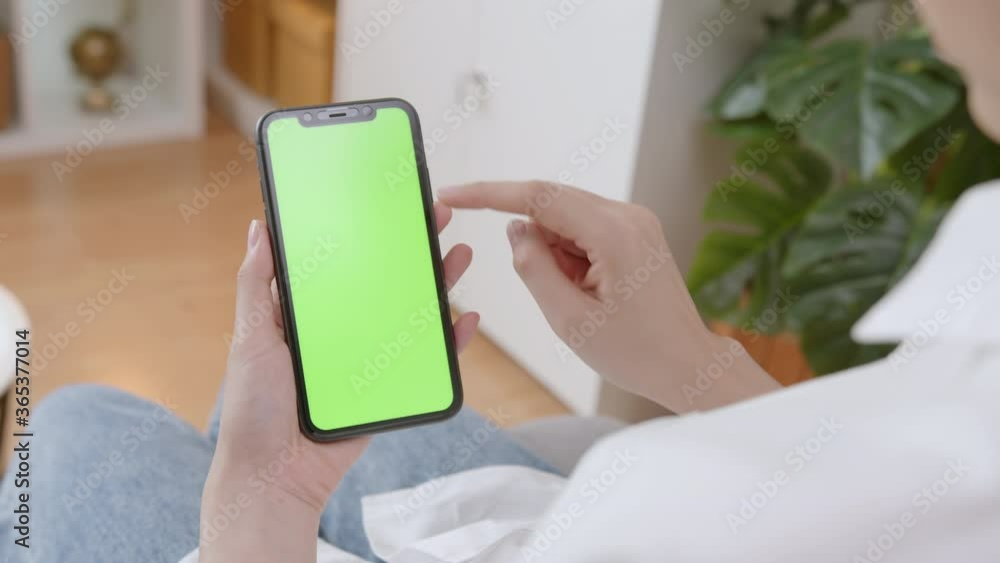 Woman holding mockup smartphone green screen on the sofa at home. Woman holding mockup smartphone green screen on the sofa at home.